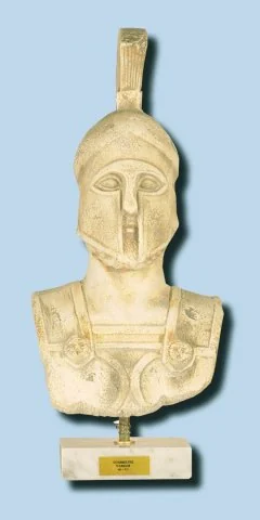 Προτομή πολεμιστή με ψηλή περικεφαλαία και διακοσμημένο θώρακα.