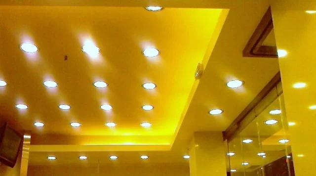 Πολυεπίπεδη οροφή με πολλαπλές σειρές χωνευτών φωτιστικών και κίτρινο φωτισμό.